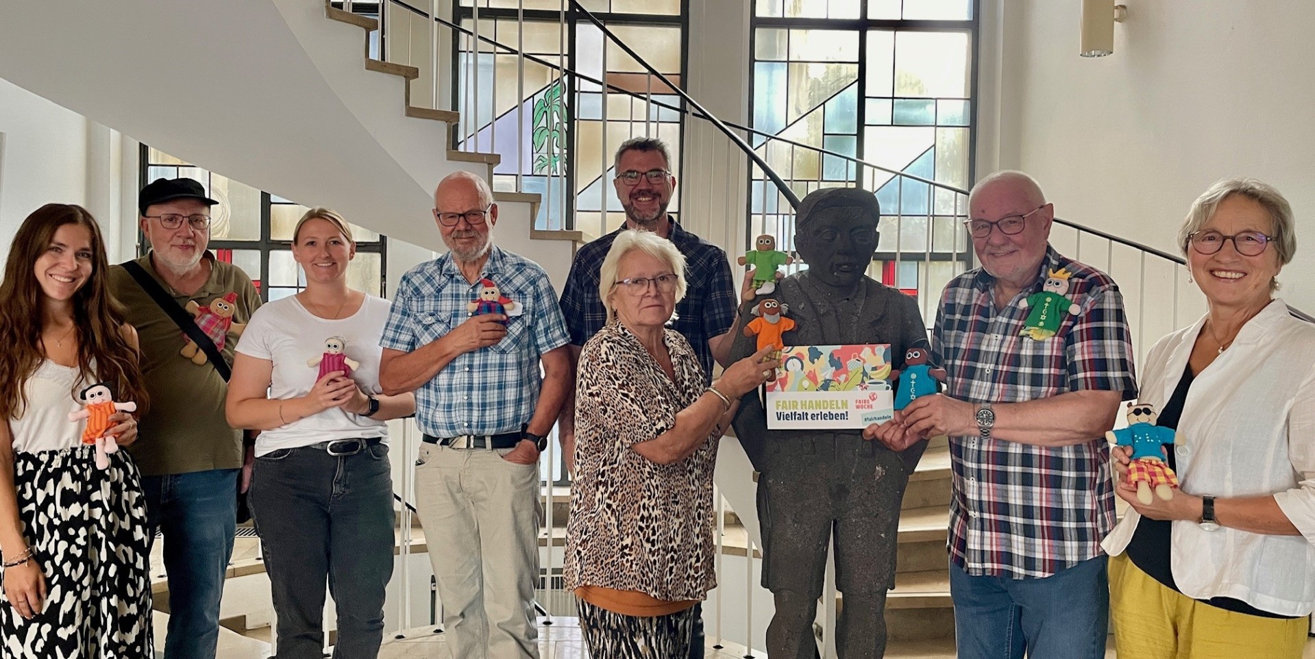 Eine Gruppe von Menschen steht für ein Foto zusammen - alle halten eine Puppe in der Hand