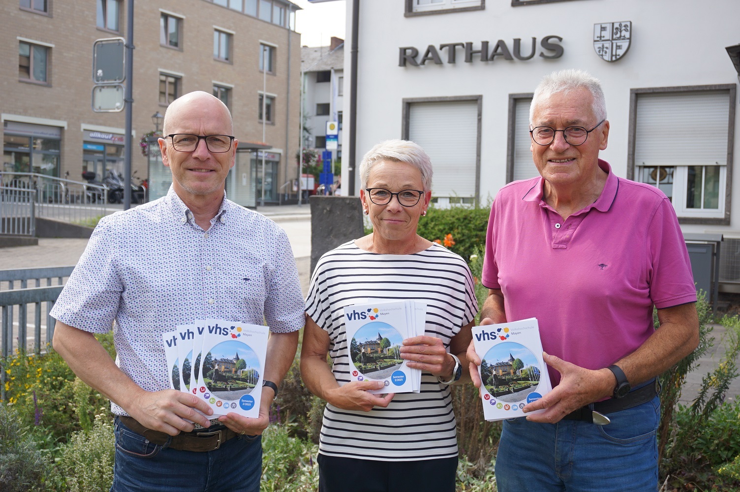 3 Personen mit einem Heft in der Hand