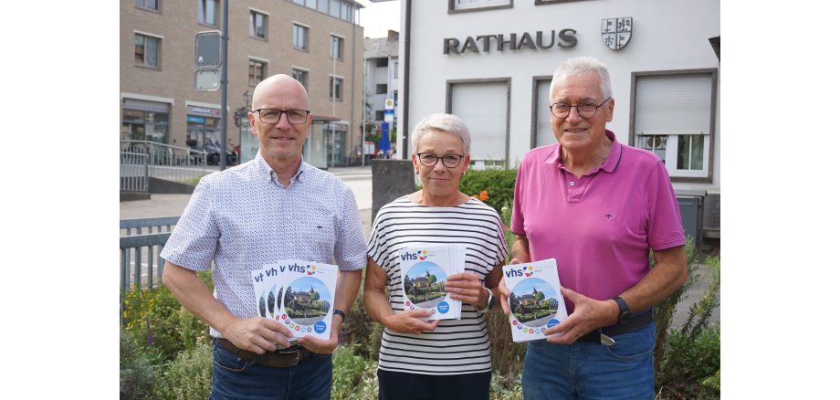 3 Personen mit einem Heft in der Hand