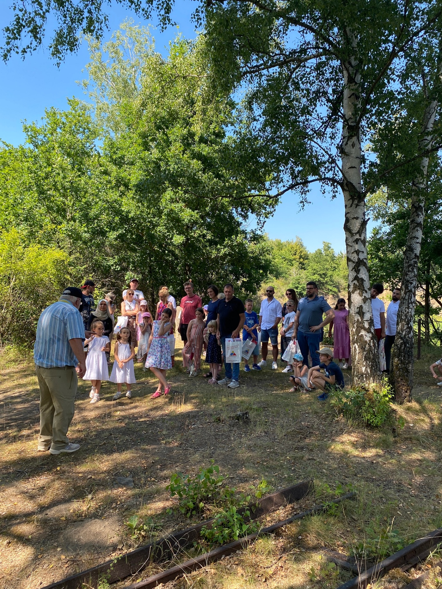 Mehrere Menschen  stehen in der Natur und folgen einer Führung
