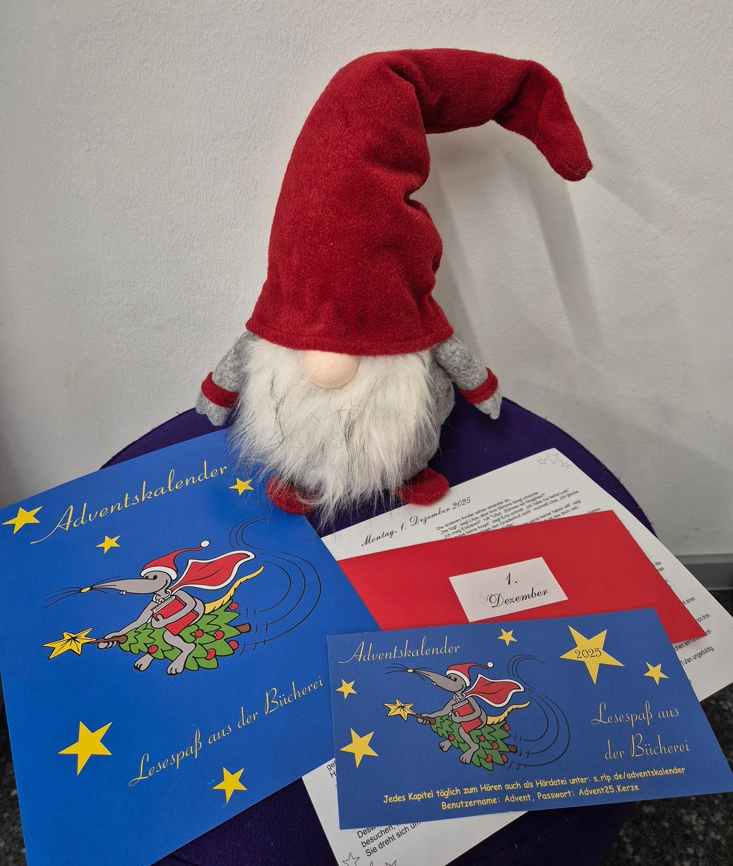 Ein Deko Weihnachtswichtel sitzt neben Kinderweihnachtsbüchern