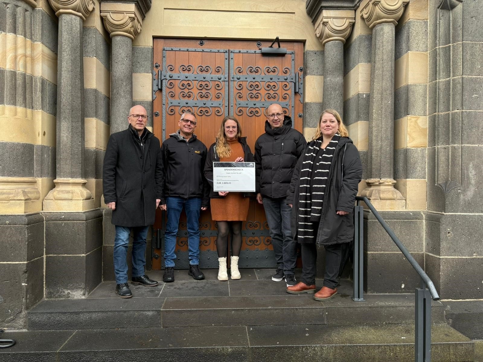 Oberbürgermeister Dirk Meid, Projektmitarbeiter Ralf Piesack, Stellv. Verwaltungsleiterin BFS Laura Wassong, Direktor Teilhabe Manuel Quint, Projektmitarbeiterin Nicole Carlsen stehen gemeinsam auf der Treppe vor der Herz Jesu Kirche