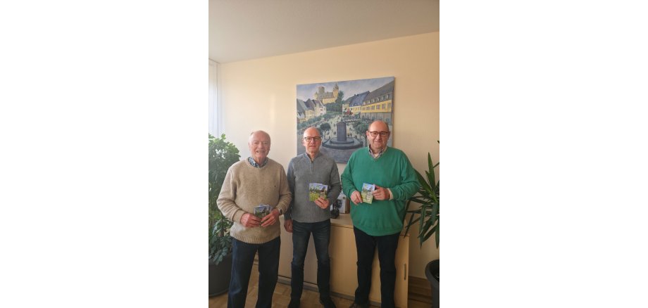 stellvertretender Vorsitzender Walter Reis, Oberbürgermeister Dirk Meid, Vorsitzender Joachim Rogalski stehen nebeneinander und halten jeweils einen Wanderplan in der Hand