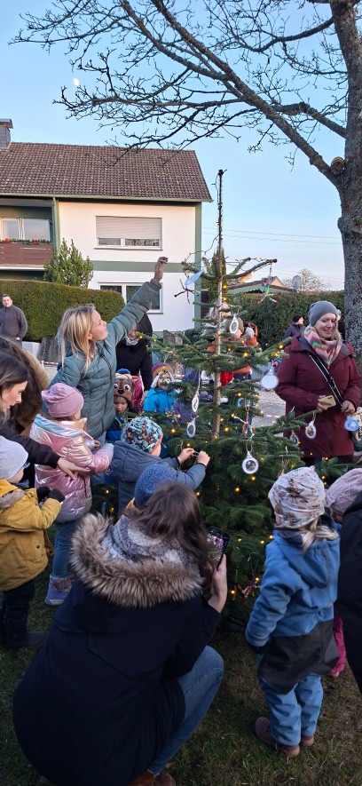 Die Kinder der KiTa Kürrenberg schmücken gemeinsam mit ihren Eltern einen Weihnachtsbaum.