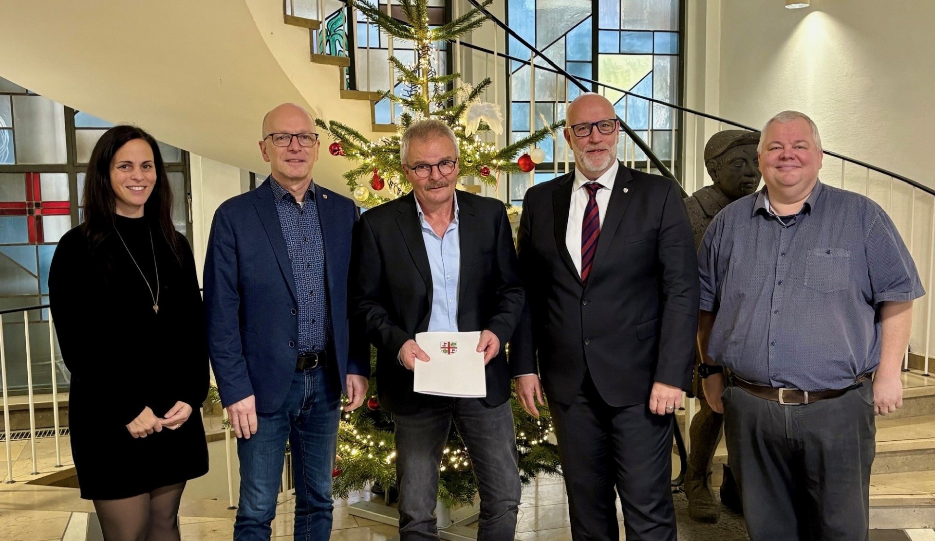 Büroleitung Jasmin Alter, Oberbürgermeister Dirk Meid, Robert Dewald, Fachbereichsleiter Uwe Hoffmann und Personalratsvorsitzender Wolfgang Goeken stehen gemeinsam vor dem festlich geschmückten Tannenbaum in der Verwaltung