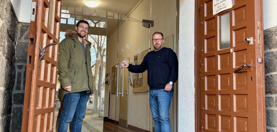 Klimaschutzmanager Helge Lippert (links) und Ortsvorsteher Sascha Flinsch stehen vor dem neuen Doppelflügel-Glaswindfang