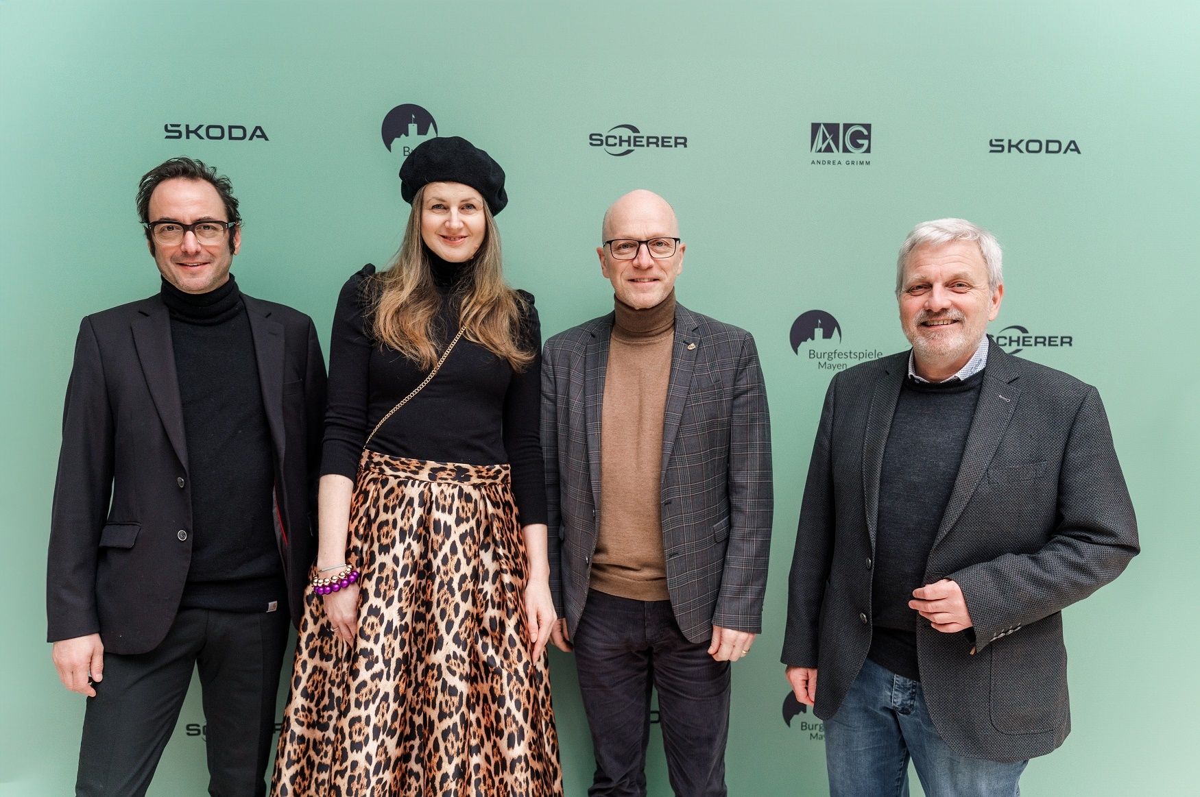 Vier Personen vor einer grünen Werbewand