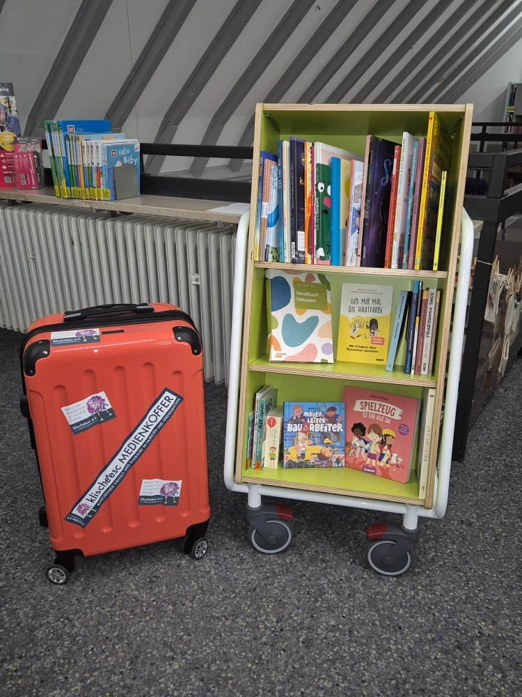 Ein Bücherregal auf Rollen mit Kinderbüchern und ein Medienkoffer