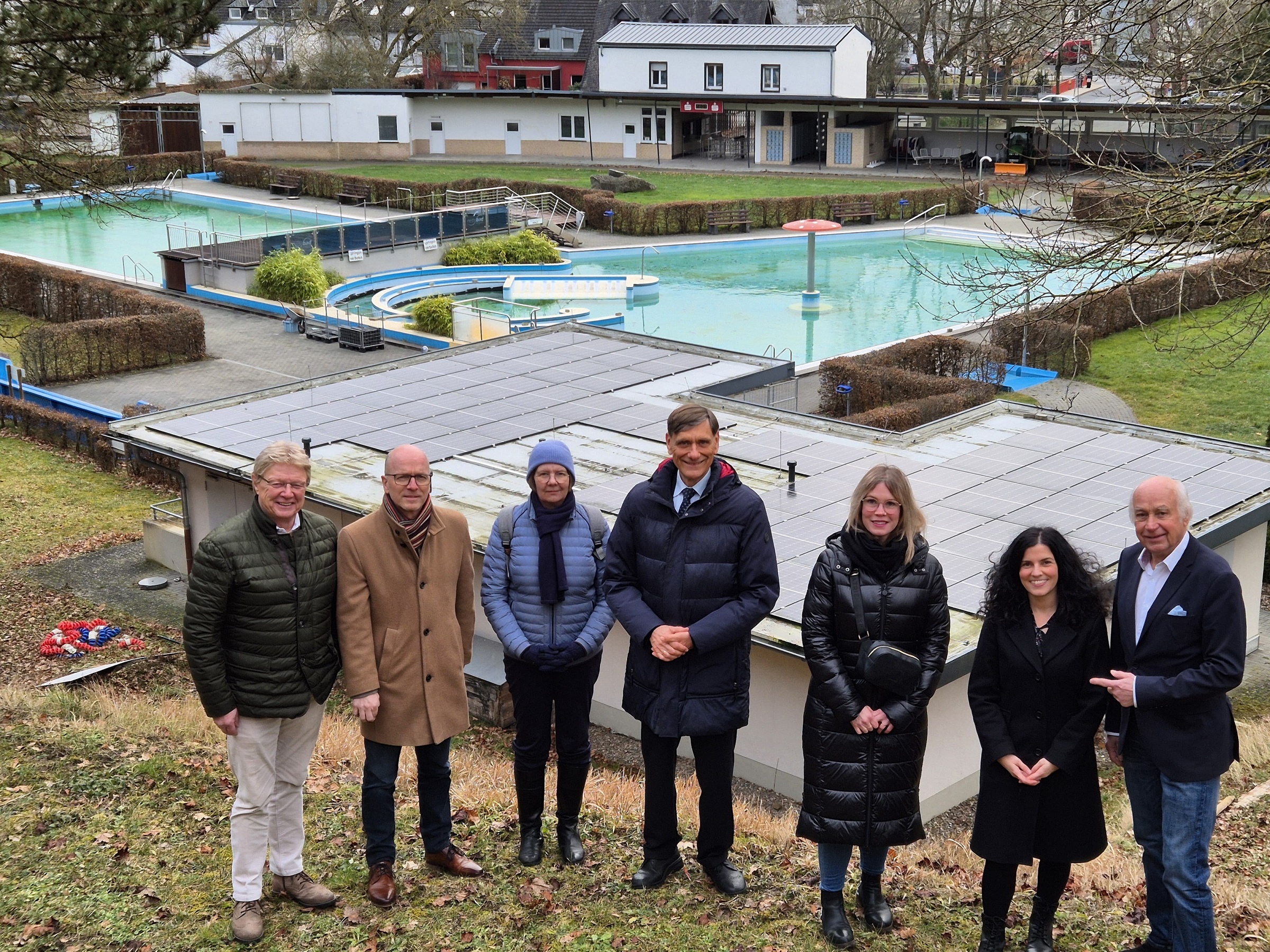 7 Personen stehe vor einem Schwimmbad für ein Foto zusammen