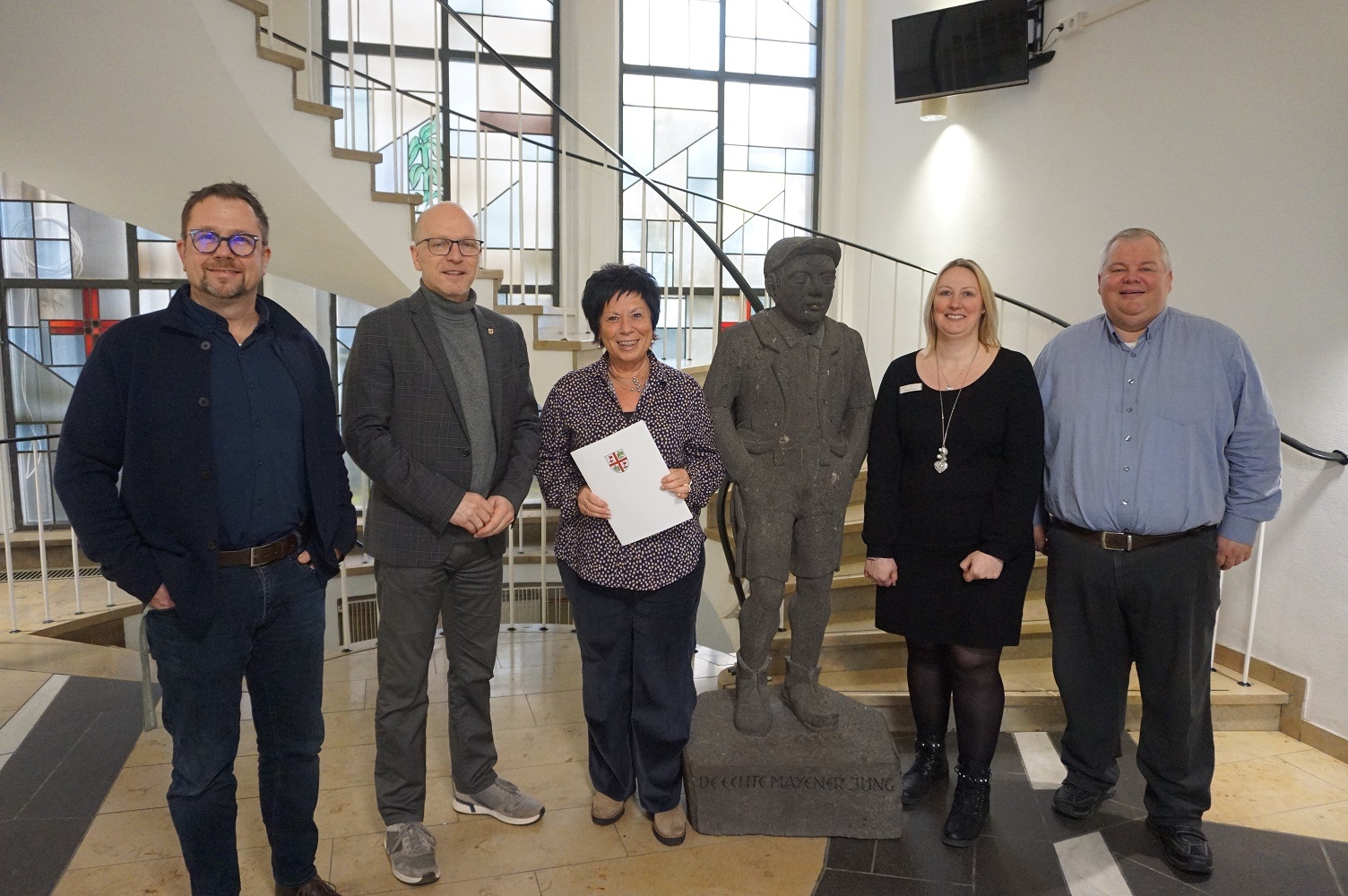 5 Personen stehen für ein Foto zusammen - eine Dame hält eine Urkunde in den Händen
