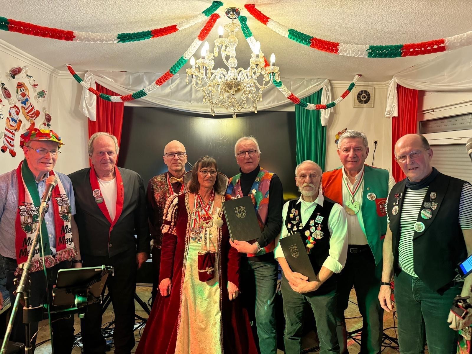 8 Personen in Kostümen stehen für ein Foto in einem geschmückten Raum zusammen