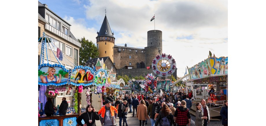 Ein gut besuchter Jahrmarkt - im Hintergrund die Burg