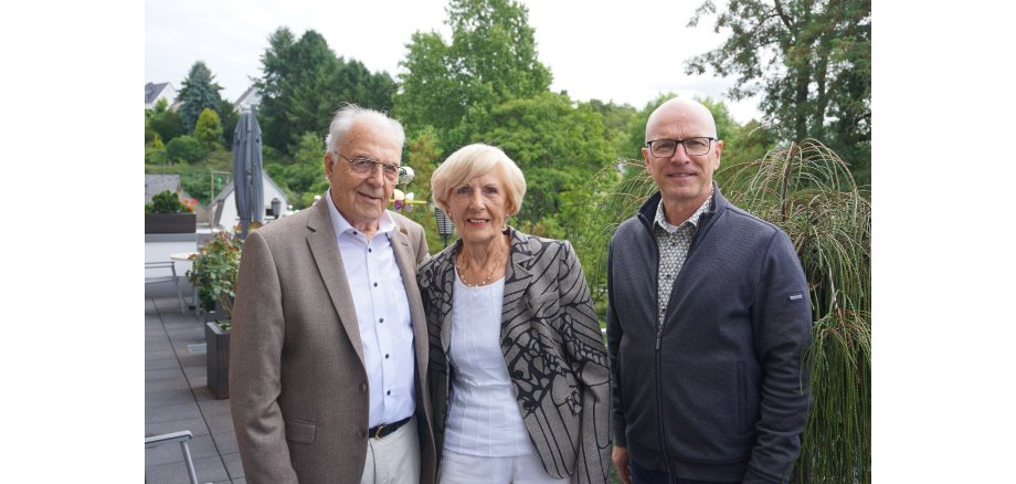 Eine Frau und zwei Männer stehen für ein Foto zusammen