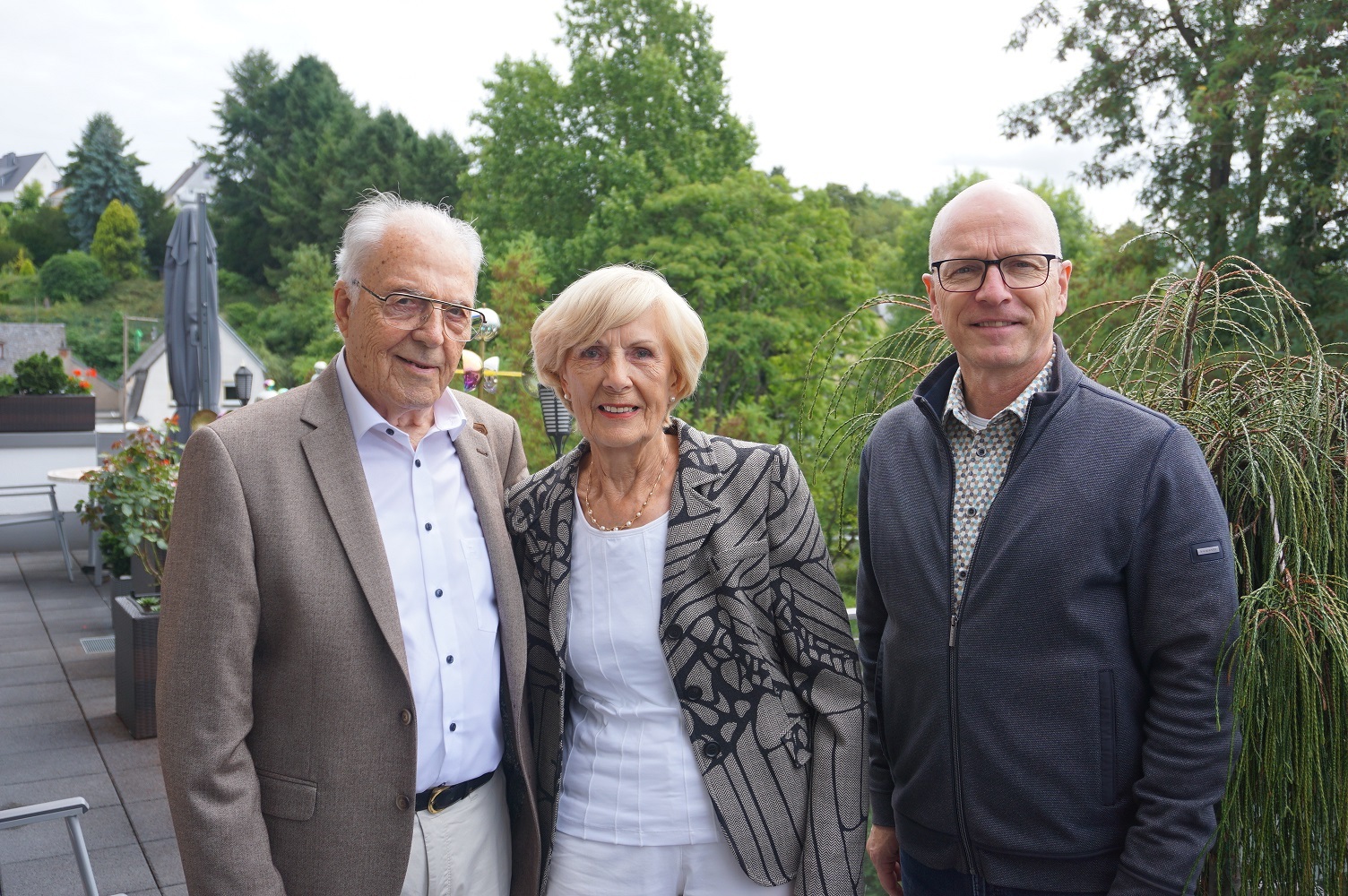 Eine Frau und zwei Männer stehen für ein Foto zusammen