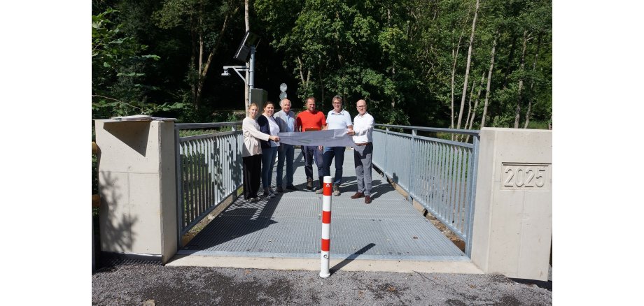 Mehrere Personen stehen auf einer Brücke und halten einen Plan in der Hand