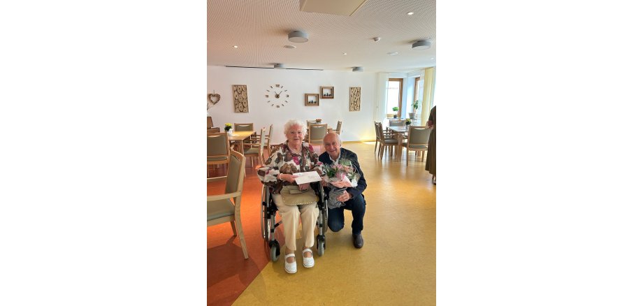 Frau sitz und Mann hoch mit Blumen daneben