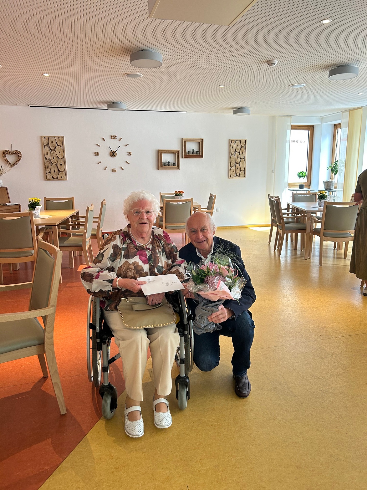 Frau sitz und Mann hoch mit Blumen daneben