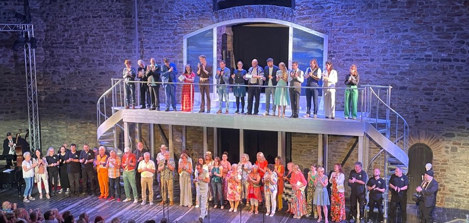 Das Ensemble der Burgfestspiele steht gemeinsam auf der Bühne im Burginnenhof