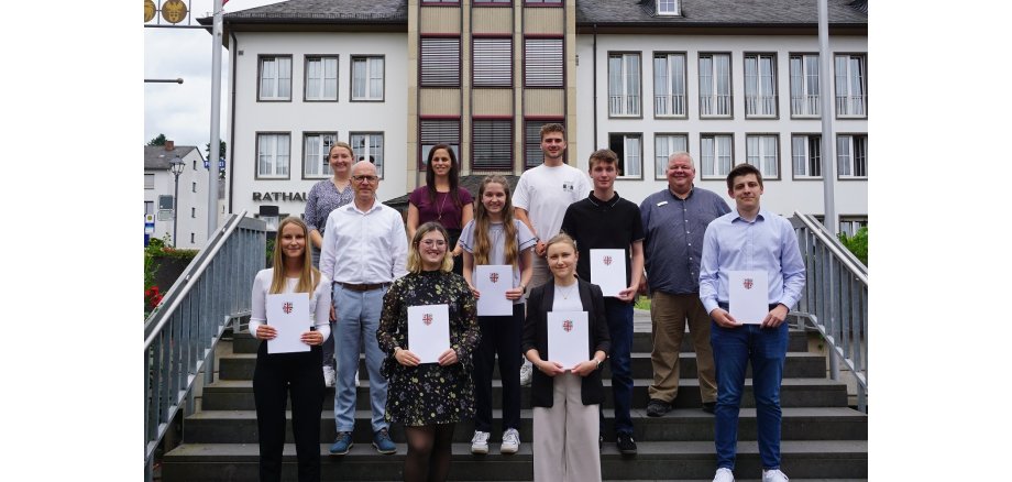 v.l.n.r.: Nele Marie Schulz, Gleichstellungsbeauftragte Janine Pitzen, Oberbürgermeister Dirk Meid, Pauline Montada, Büroleiterin Jasmin Alter, Nina Lauter, Marius Luxem von der JAV, Emilie Hill, Ben Randy Franzen, Personalratsvorsitzender Wolfgang Goeken und Mario Vallendar Mehrere Personen stehen für ein Gruppenfoto auf einer Treppe vor dem Verwaltungsgebäude