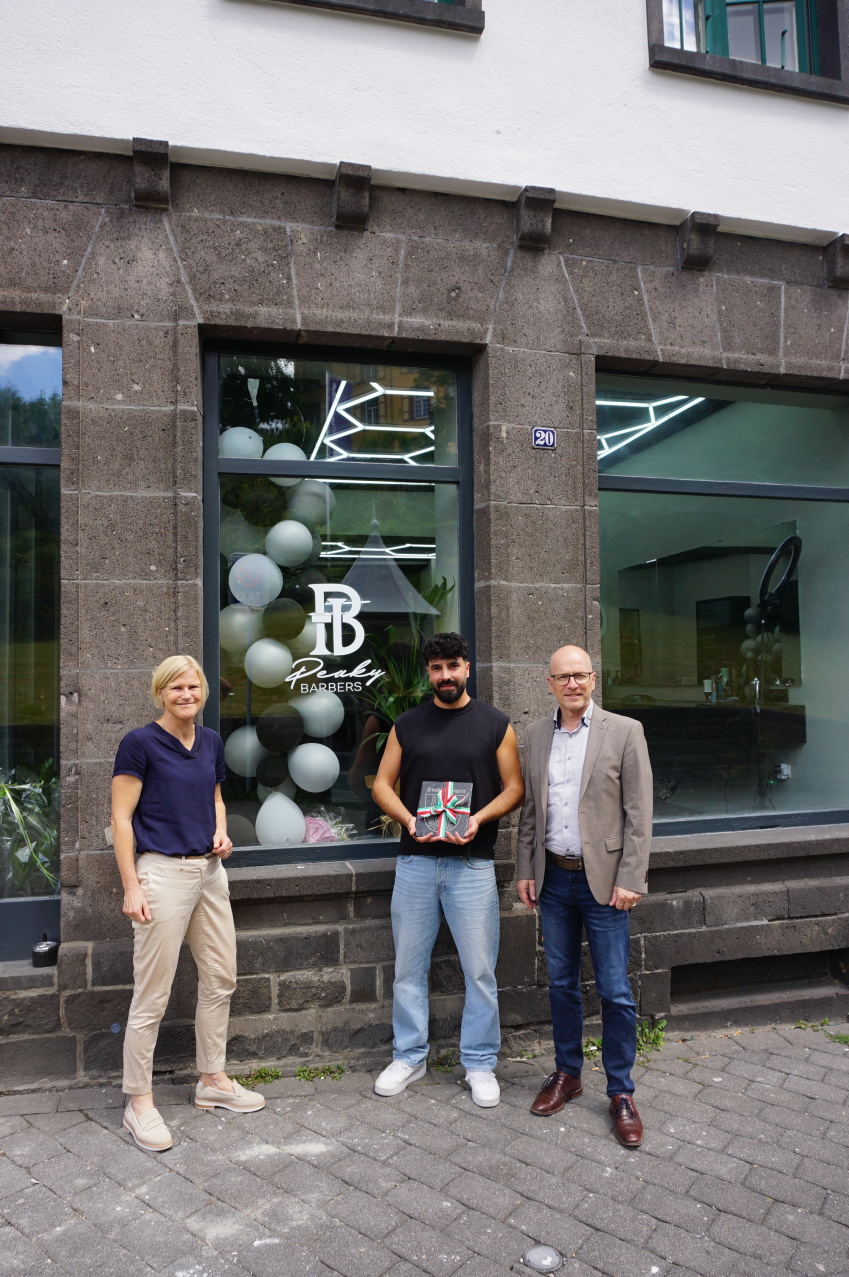 3 Personen stehen vor einem Laden