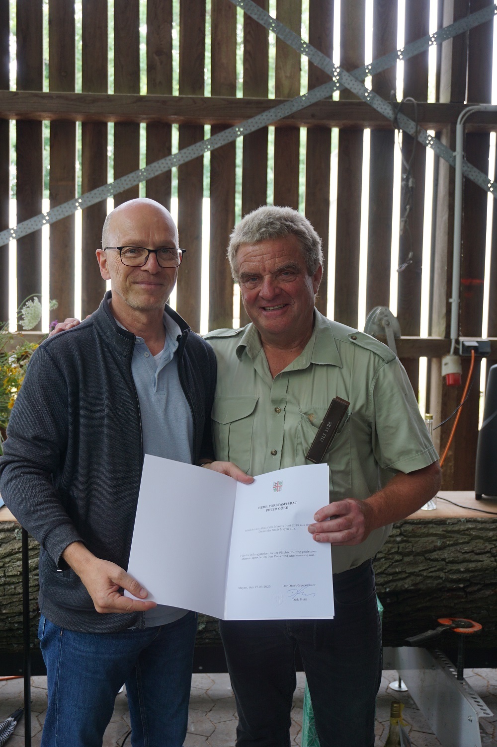 Zwei Personen stehen für ein Foto zusammen - einer hält eine Urkunde in der Hand