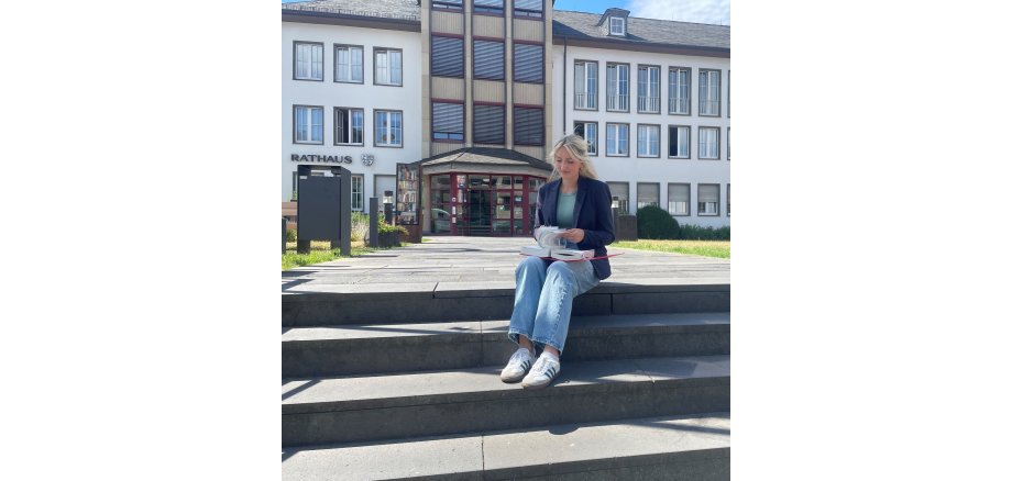 Eine Frau sitzt auf einer Treppe und blättert in einem Gesetzbuch