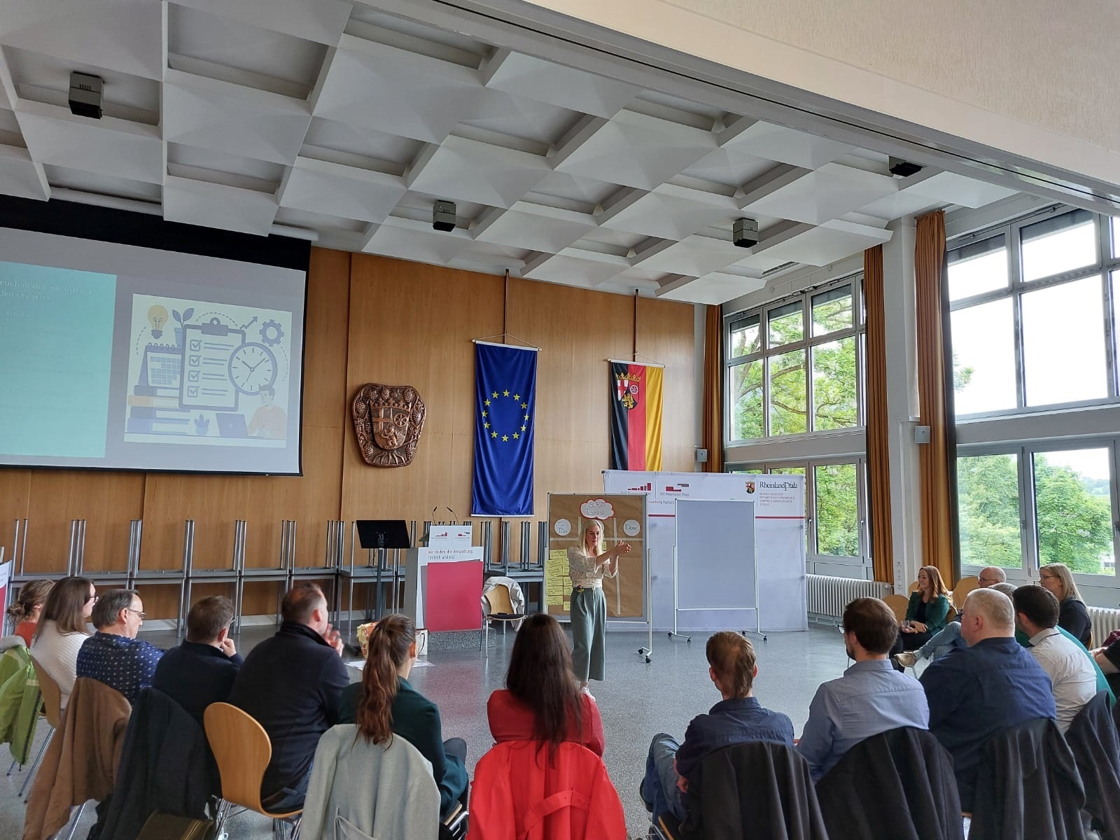Mehrere Menschen sitzen in einem Halbkreis zusammen und hören einer Frau zu