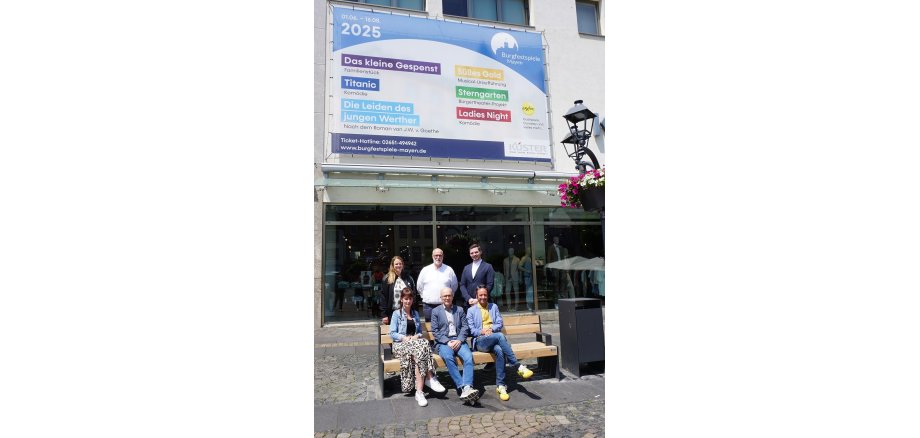 Sechs Personen stehen vor dem Werbebanner