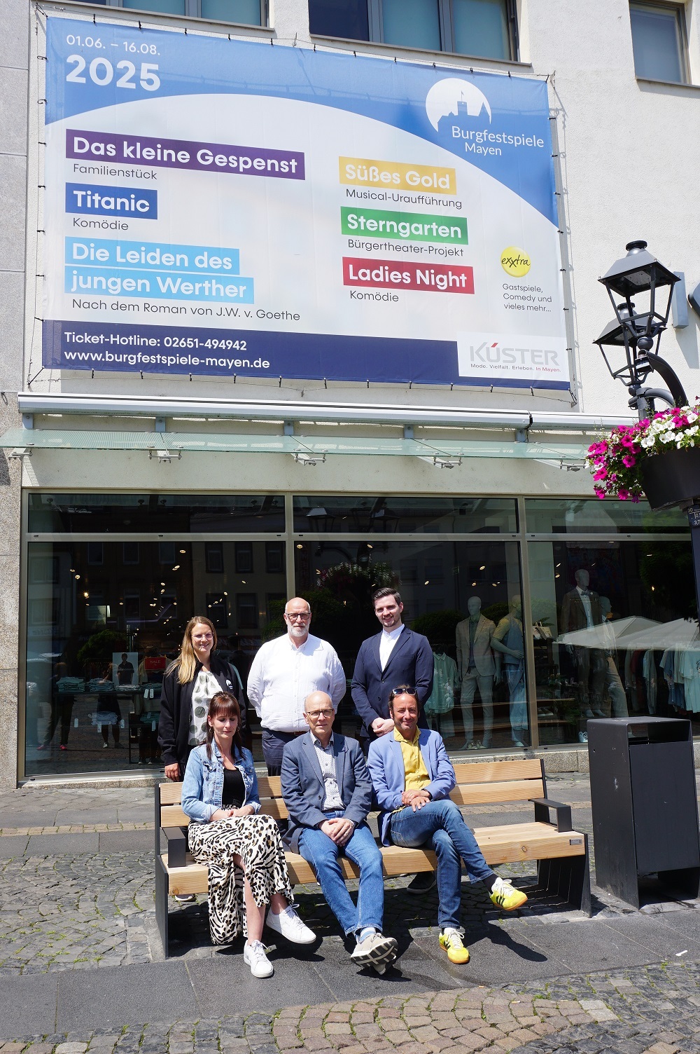 Sechs Personen stehen vor dem Werbebanner