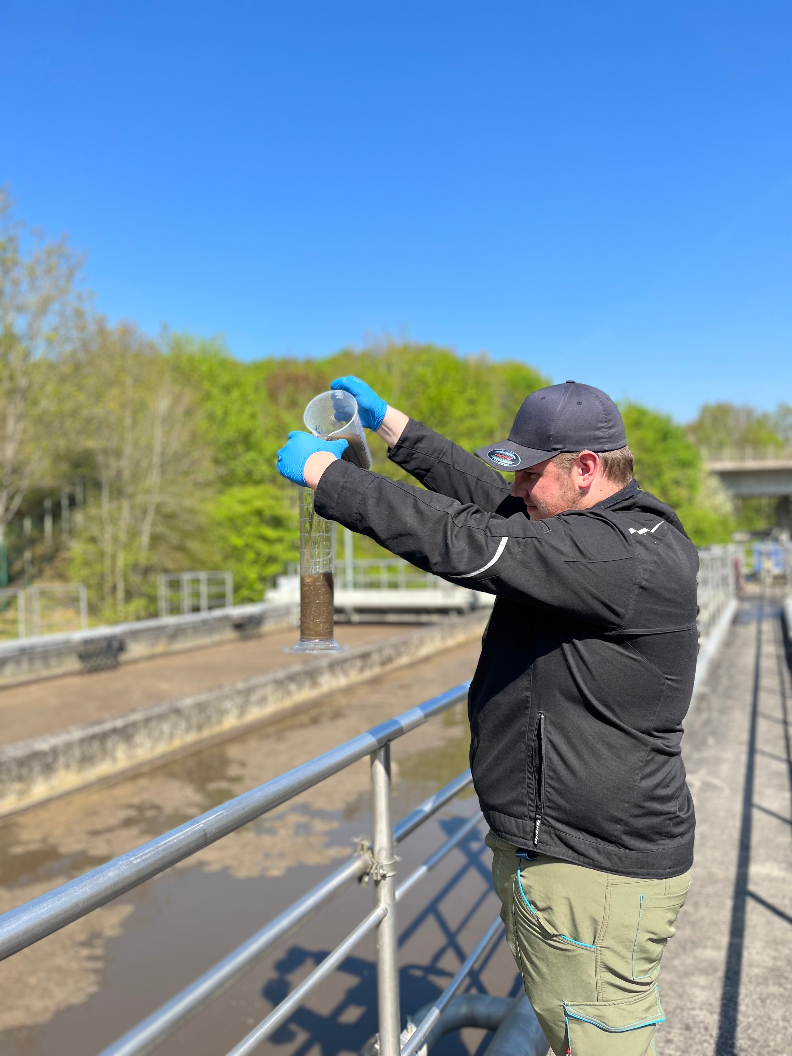 Junge steht am Abwasserbecker und nimmt eine Probe