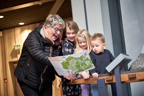 Eine Frau und drei Kinder betrachten im Museum eine Karte