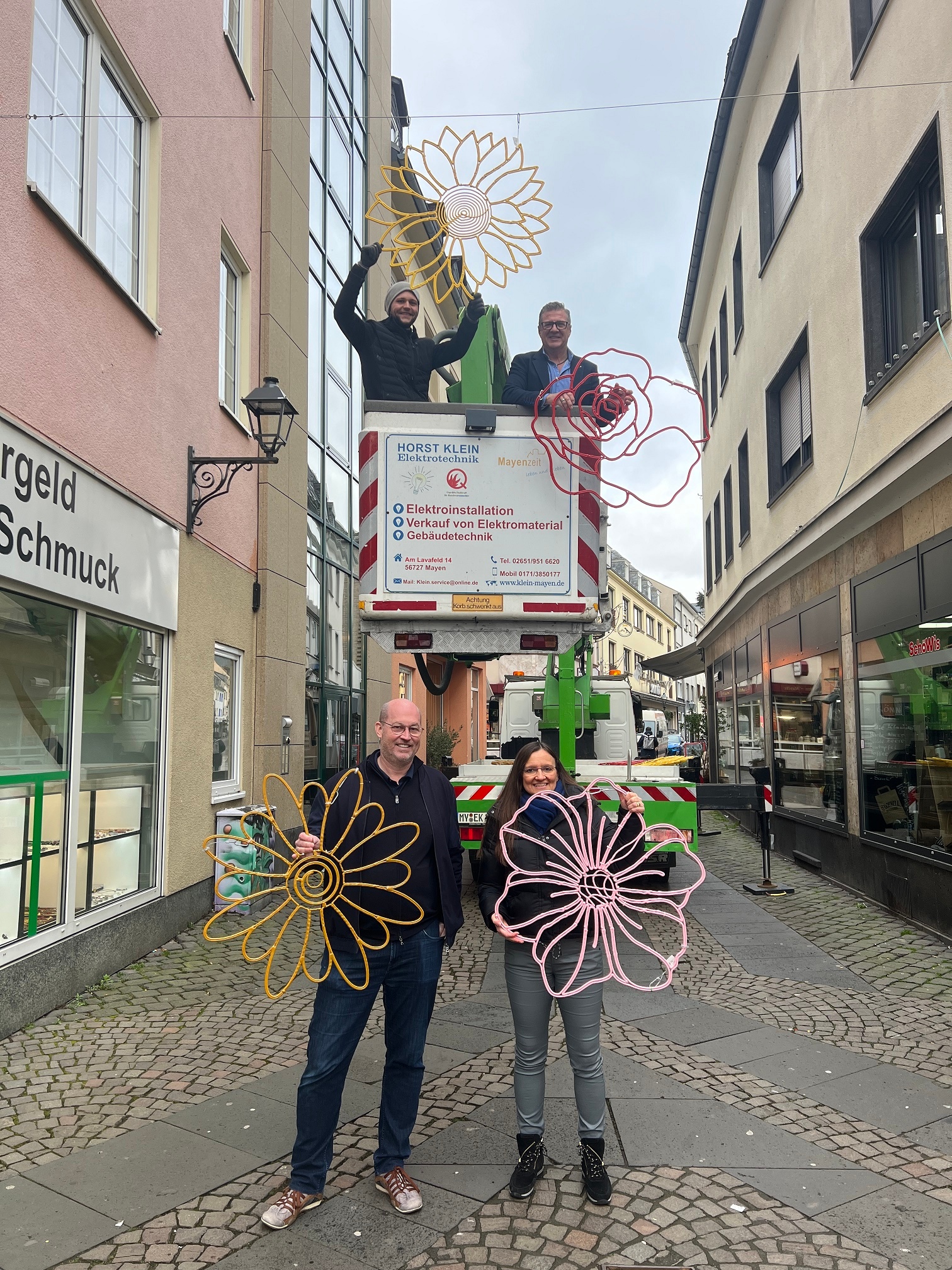 Insgesamt vier Personen, 2 davon auf einem Steiger bringen die neue Dekoration an