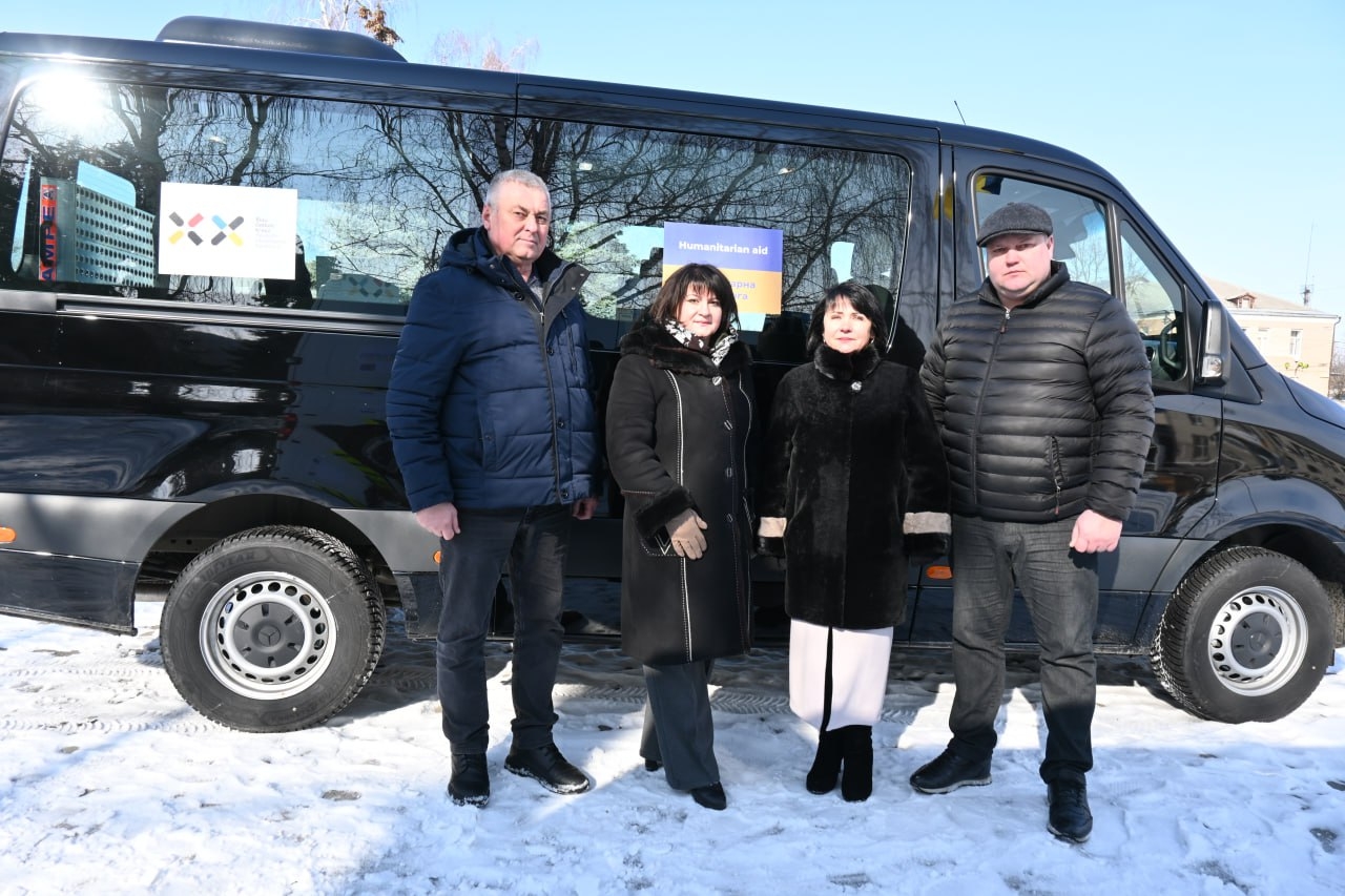 4 Personen stehen vor einem schwarzen Bus