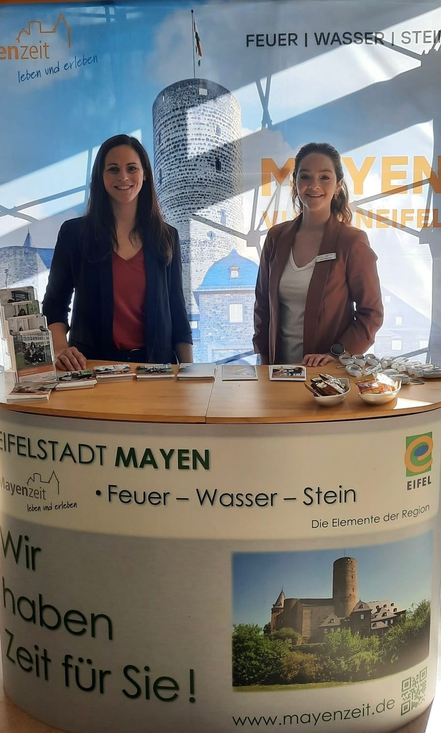 Büroleiterin Jasmin Alter (links) und Personalentwicklerin Anne Schomisch (rechts) an einem Stand der Stadtverwaltung Mayen Zwei Personen hinter einem Messestand