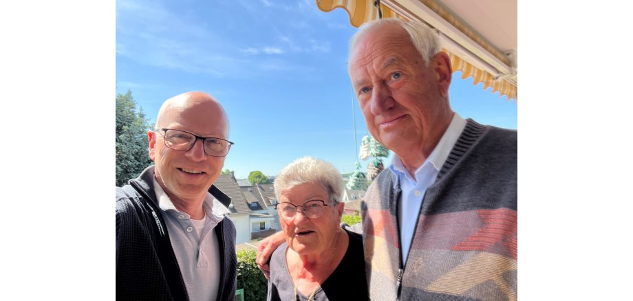 OB Meid posiert mit den Eheleuten Karbach draußen.