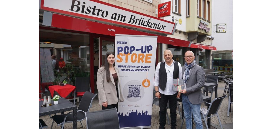 3 Personen und ein Roll-Up stehen vor dem neuen Bistro