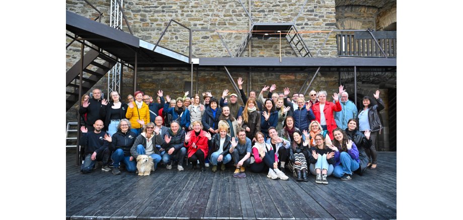 Viele Menschen posieren zusammen auf der Bühne der Burgfestspiele