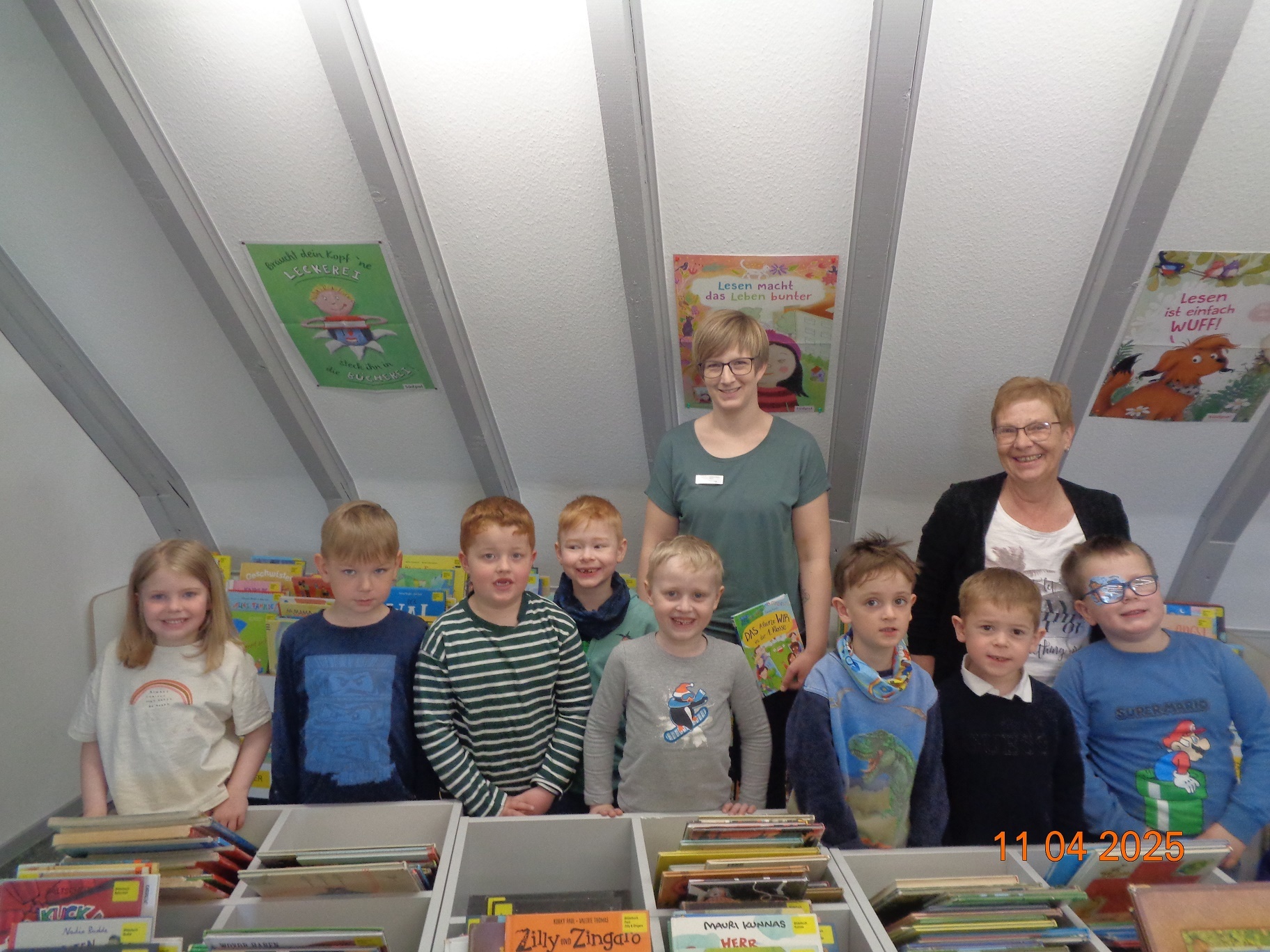 Eine Gruppe aus Kindern und Erwachsenen in einer Bücherei 