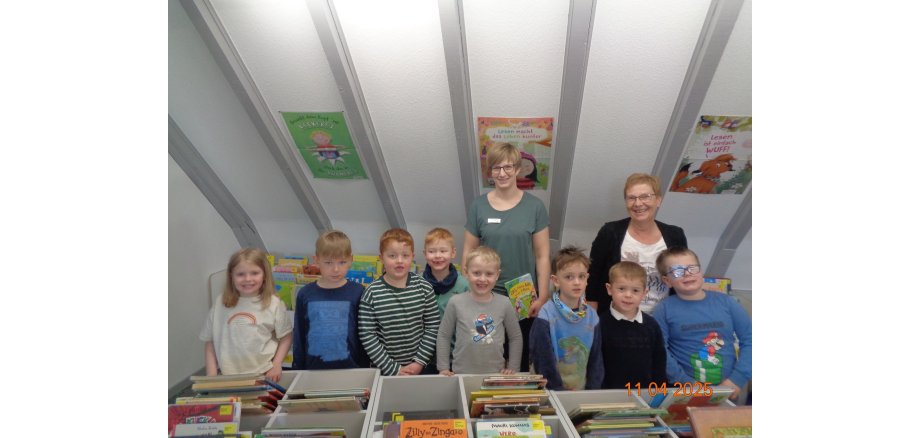 Eine Gruppe aus Kindern und Erwachsenen in einer Bücherei 