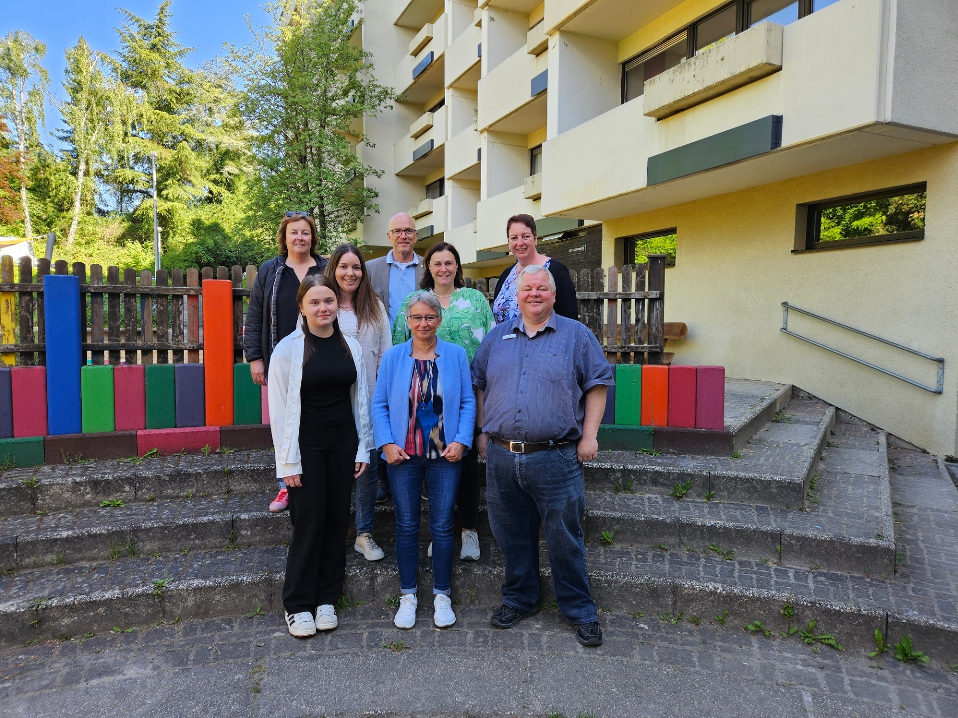 Acht Personen posieren auf einer Treppe