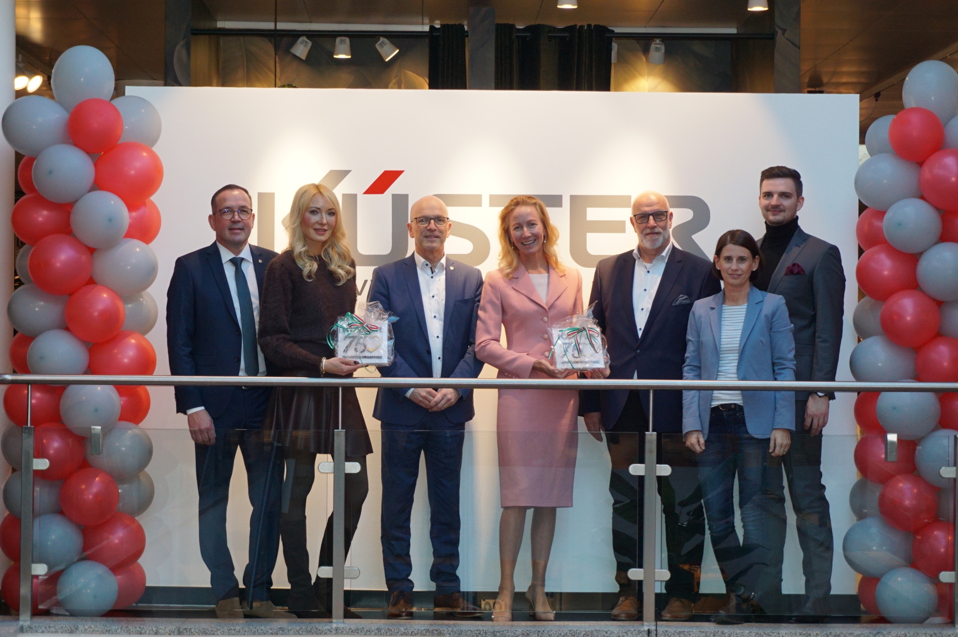 Einige Personen vor dem Firmenlogo Küster mit Ballons