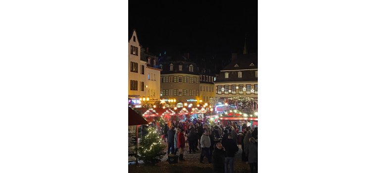 Festlicher Weihnachtsmarkt im dunkeln mit vielen Lichtern und Besuchern