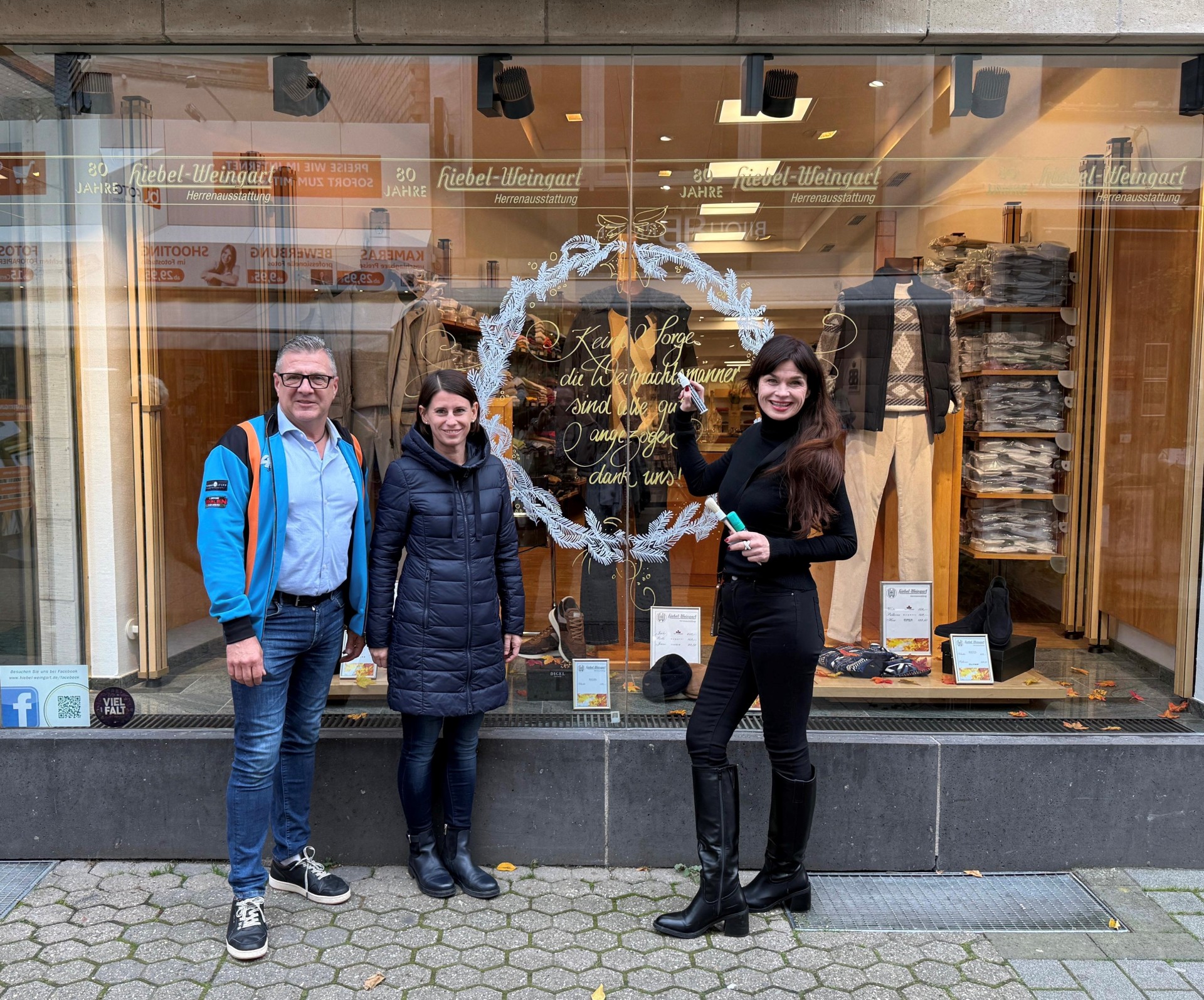 3 Personen stehen in der Innenstadt vor einem bemalen Fenster