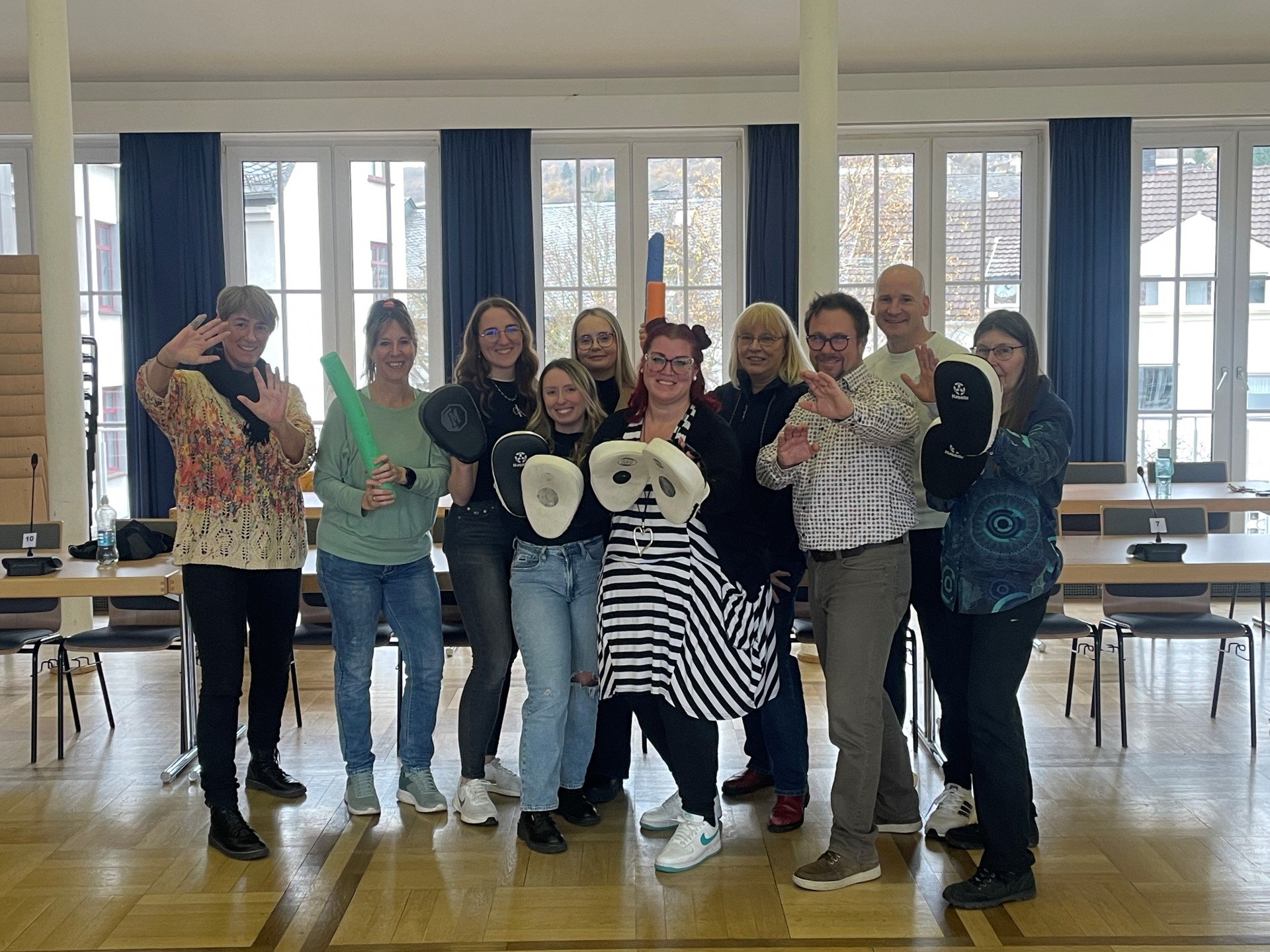 Der Selbstverteidigungskurs traf bei den Mitarbeitenden auf große Begeisterung Zehn Menschen stehen gemeinsam im Sitzungssaal und halten Hilfsmittel zur Selbstverteidigung in der Hand