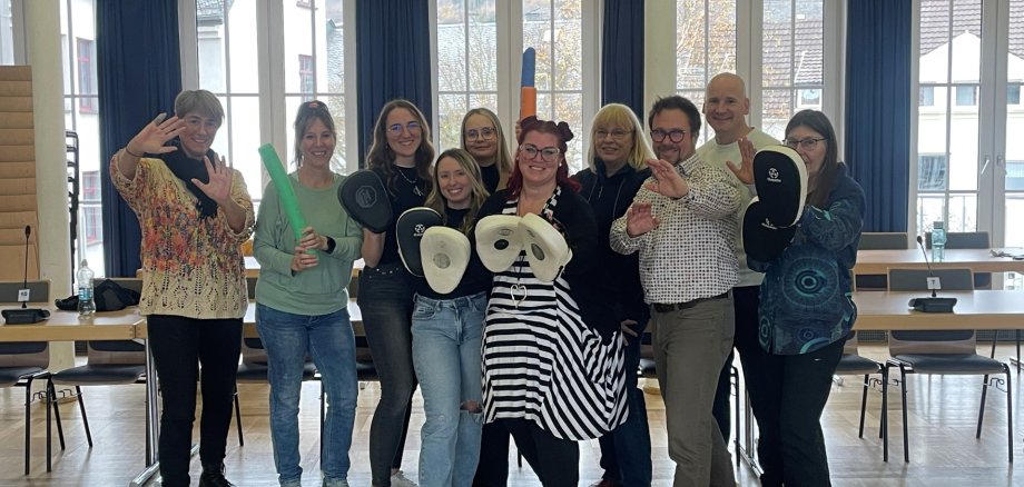 Der Selbstverteidigungskurs traf bei den Mitarbeitenden auf große Begeisterung Zehn Menschen stehen gemeinsam im Sitzungssaal und halten Hilfsmittel zur Selbstverteidigung in der Hand