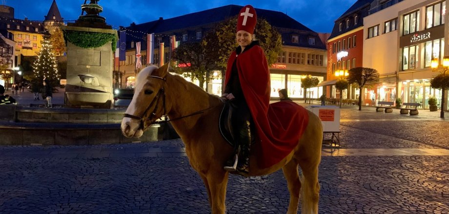 Martinsdarstellerin Alina Rübenach sitzt im Martinsgewand auf einem Pferd.