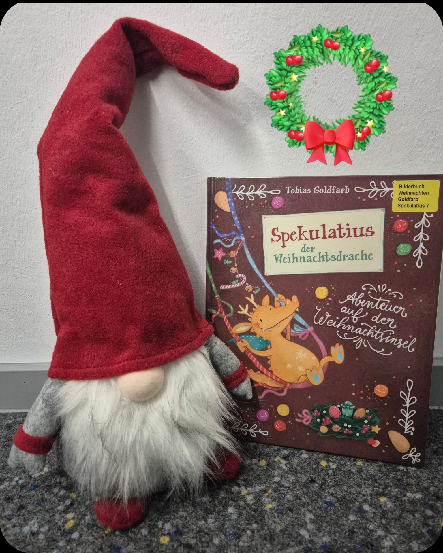 Ein Deko Weihnachtswichtel sitzt neben einem Kinderbuch