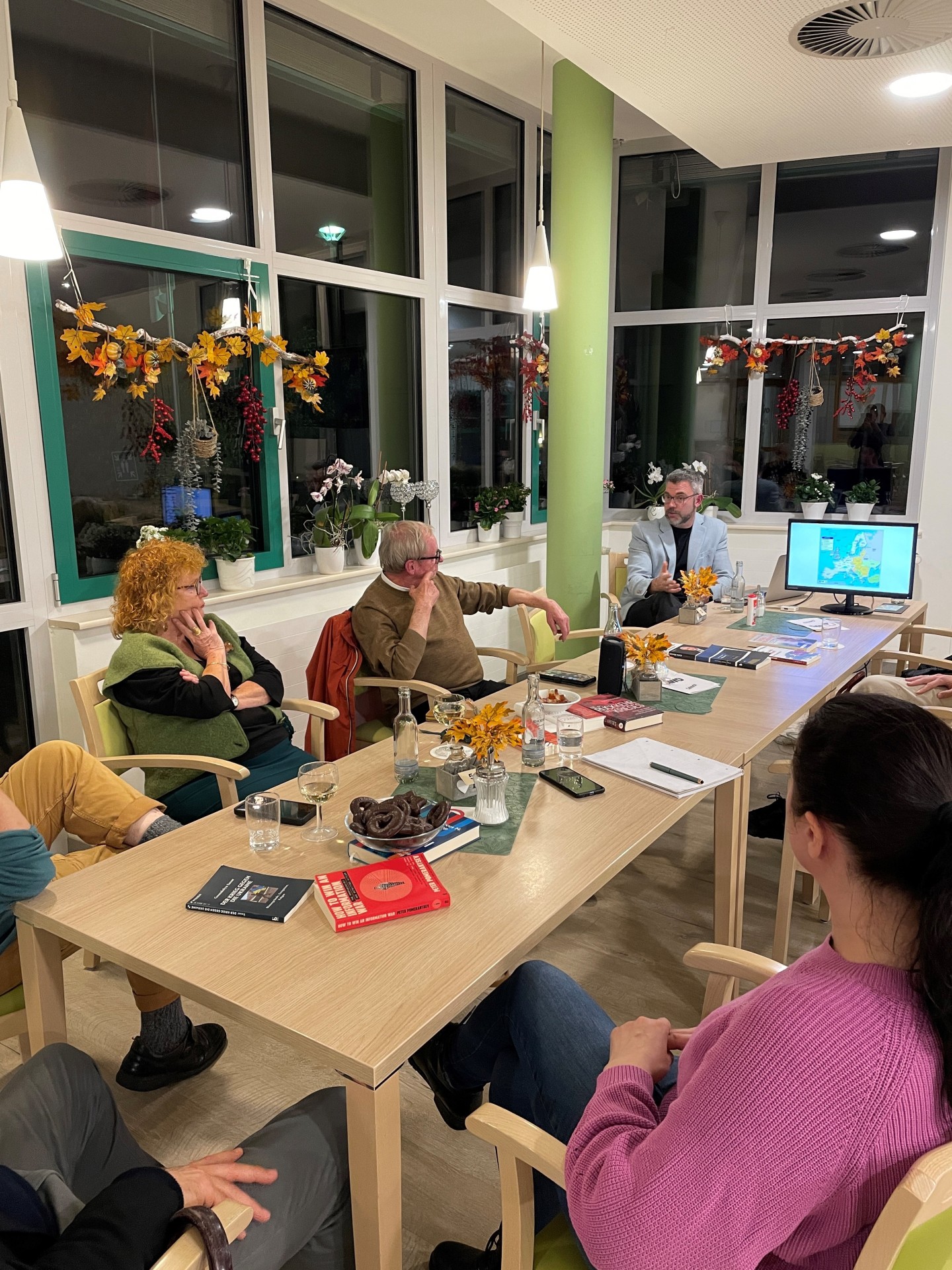 Was steckt hinter einer Solidaritätspartnerschaft? – das war eines der Themen an diesem Abend Fünf Menschen sitzen gemeinsam an einem Tisch und hören aufmerksam dem Vortrag zu.