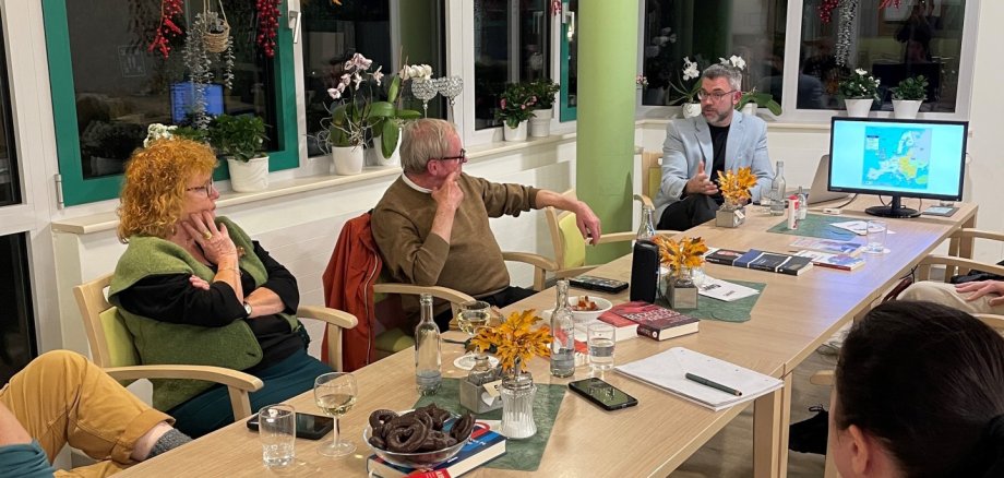 Was steckt hinter einer Solidaritätspartnerschaft? – das war eines der Themen an diesem Abend Fünf Menschen sitzen gemeinsam an einem Tisch und hören aufmerksam dem Vortrag zu.