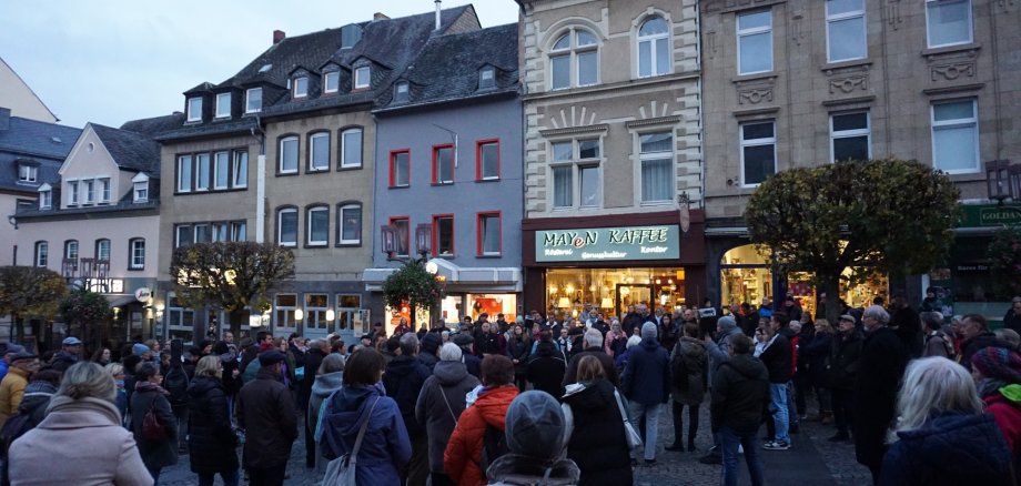 Viele Menschen stehen gemeinsam bei Dämmerung auf dem Marktplatz